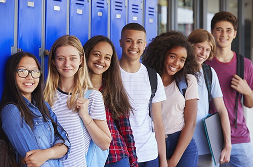 Teenage school kids smiling to camera in school corridor